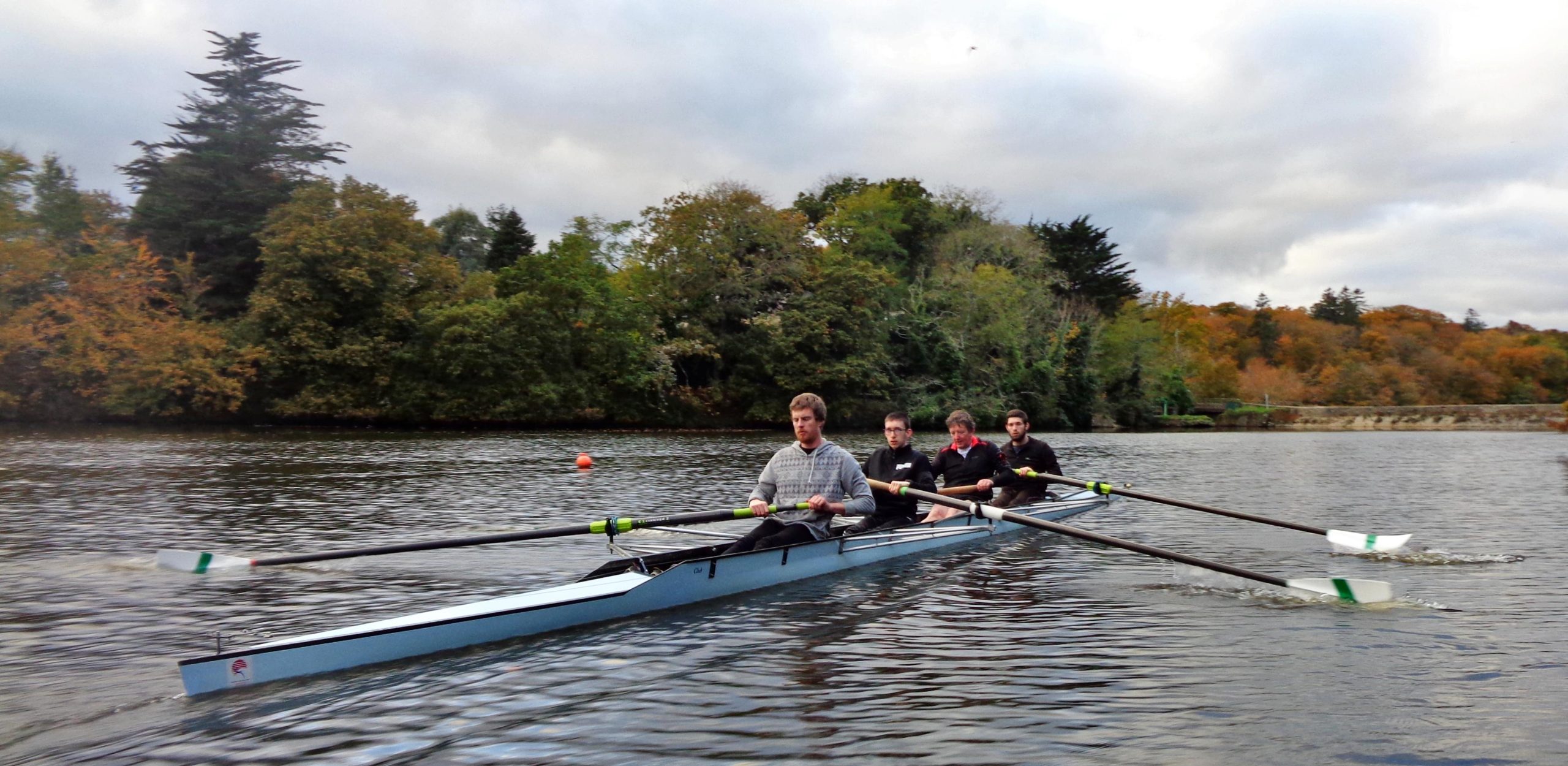 Un groupe d'hommes faisant de l'aviron sur l'étang du Ter sur un quatre sans barreur